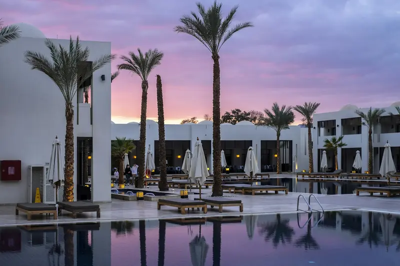 Resort at dusk beside a lit swimming pool